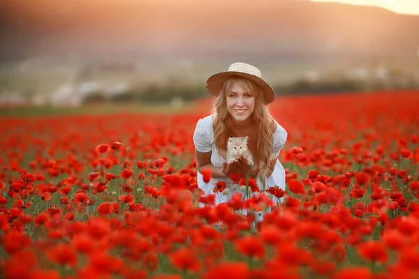 Eine schöne Frau mit Strohhut auf einem landwirtschaftlichen Feld mit Mohn — Stockfoto
