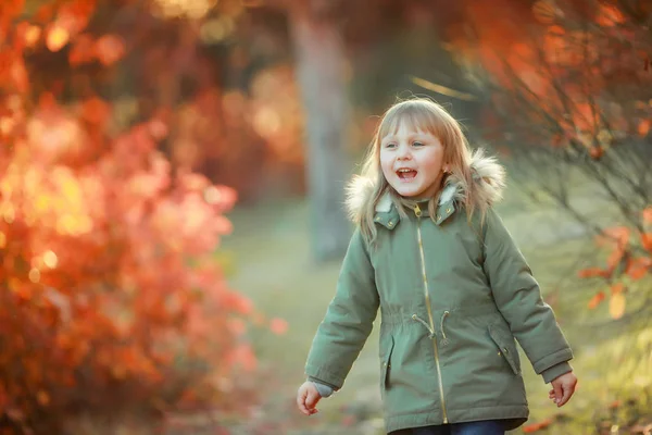Chica feliz con el pelo blanco en una chaqueta caliente caminando cerca de los árboles y respirando aire limpio —  Fotos de Stock