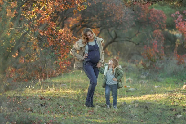 Mother and daughter together go through the woods with falling yellow leaves — Stock Photo, Image