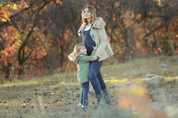 Мать и дочь вместе идут через лес с падающими жёлтыми листьями — стоковое фото