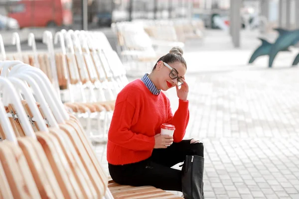Schöne Frau mit Brille sitzt auf der Straße und trinkt Kaffee — Stockfoto