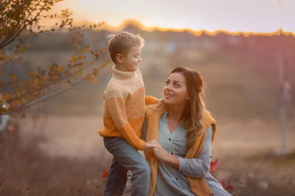 Mutter mit Sohn setzte sich auf den Rasen aus trockenem, gelbem Gras beim Gehen — Stockfoto