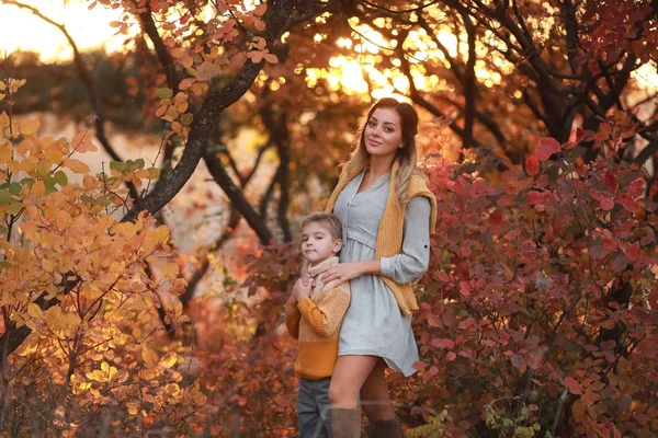 Moeder en zoon wandelen samen in het park in de herfst in warme kleren — Stockfoto