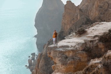 Genç bir çift taş bir dağın tepesinde birbirine sarılır kayalardan oluşan bir arka planda