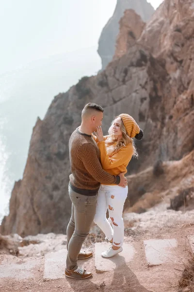 若い男が石の山を背景に山の上に最愛の女性を抱きしめる — ストック写真