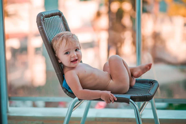 Bayi beristirahat di kursi yang nyaman di udara segar di latar belakang hotel yang tidak fokus — Stok Foto