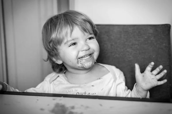Foto en blanco y negro de un niño que come sin usar un tenedor o cuchara manchada con comida — Foto de Stock