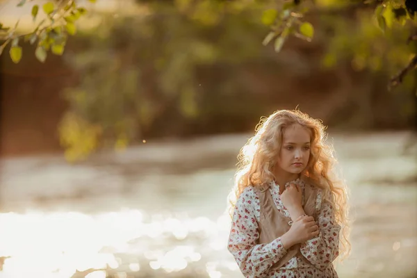 Fiatal, komor szőke nő pózol a folyóparton. Fényképezés élénk színekben — Stock Fotó