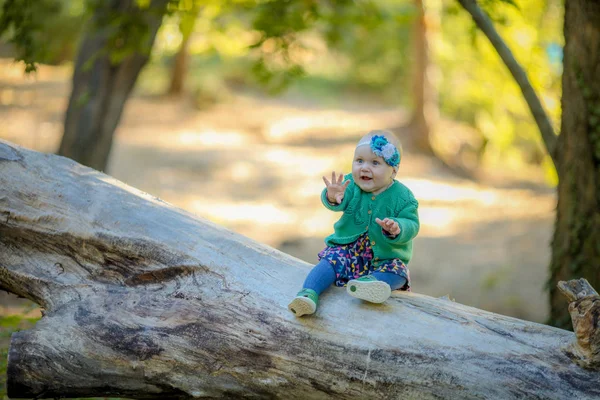 Baby meisje zitten op een boomstam en glimlachen genieten van het leven — Stockfoto