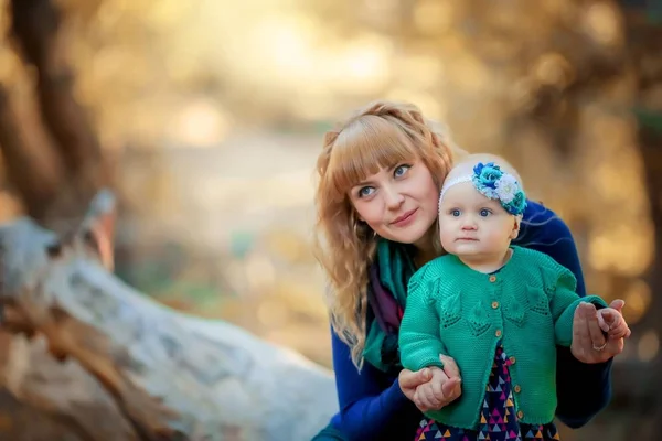 El niño da sus primeros pasos con la ayuda de su madre en el aire fresco en el bosque —  Fotos de Stock