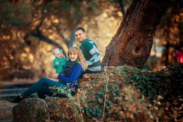 Family with baby mom and dad sitting under a tree in the forest and happines together — Stock Photo, Image