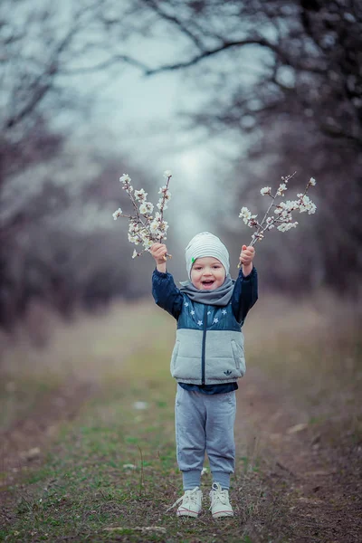 Niño al aire libre en chaqueta de otoño y gorra en el fondo de un jardín con árboles —  Fotos de Stock