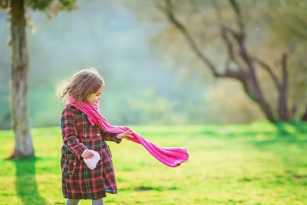 Dívka 7-8 let v teplém kabátě procházky na začátku jara na zelené louce — Stock fotografie