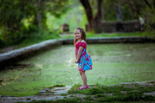 Dívka hrající v přírodě v blízkosti jezera pokryté zelenými řasami — Stock fotografie