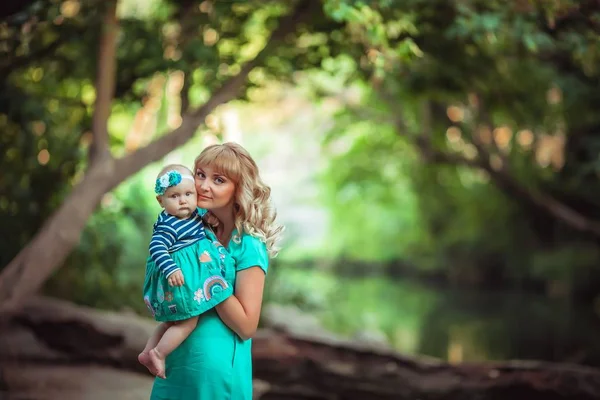 En familj med två personer mor och dotter barn sitter i naturen nära sjöar och mellan träd — Stockfoto