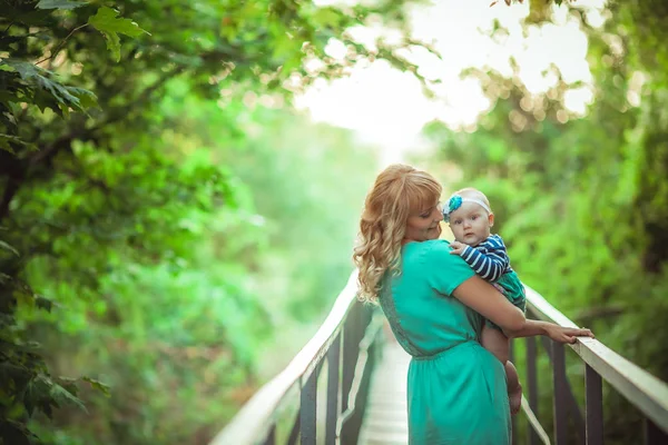 Mutter wandert mit Kind in der Natur und geht auf Waldweg über die Brücke — Stockfoto