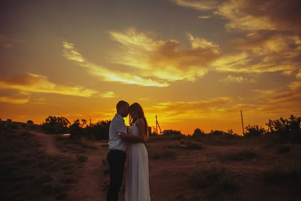 Romantische foto van twee geliefden op de achtergrond van een felgele zonsondergang — Stockfoto
