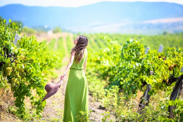 Jovencita la dueña del campo de uva camina en un hermoso vestido elegante en el verano en el campo de uva —  Fotos de Stock