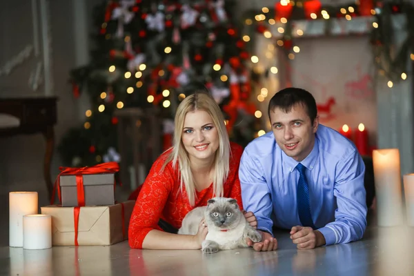 一对男女新婚夫妇躺在壁炉边的肚子上，旁边是他们的圣诞礼物 — 图库照片
