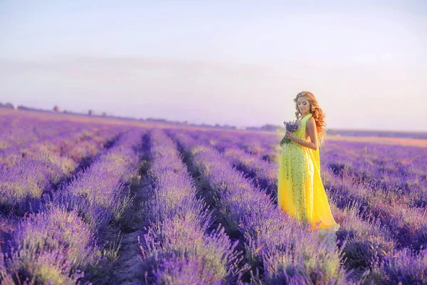 Femme avec un bouquet dans un champ de jeune lavande un jour de printemps — Photo