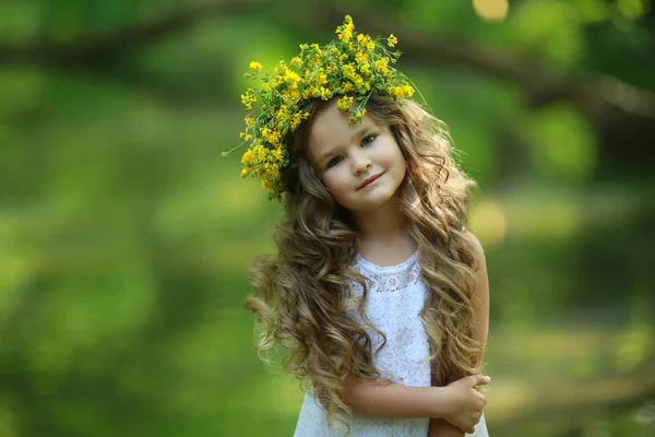 Retrato de uma menina de 6-8 anos com uma coroa de flores na cabeça ao ar livre — Fotografia de Stock