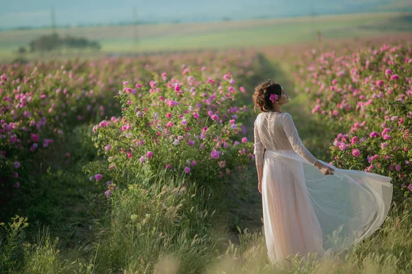 Femme dans une robe de mariée avec une fleur poignardée dans la tête dans une longue robe de fête légère — Photo