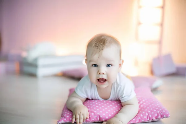 Anak kecil di bawah umur 1 tahun berbaring di sebuah ruangan di atas bantal merah muda pada hari ulang tahunnya — Stok Foto