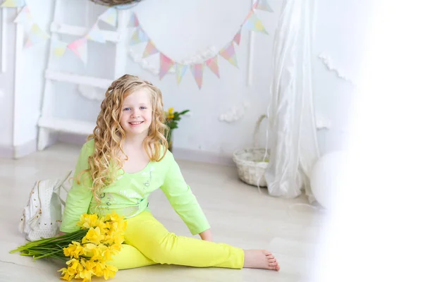 Usmívající se dívka školního věku se žlutými květy v rukou — Stock fotografie