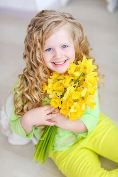Stüdyodaki kıvırcık sarı saçlı kız elinde bir buket sarı çiçekle — Stok fotoğraf