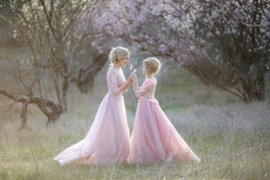 Anne ve kızı bahçede pembe eski moda elbiseler içinde.