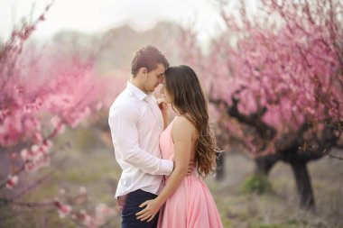Romantik damat Gelin alın duvarın karşısında dururken öpüşme pembe çiçeklerle kaplı
