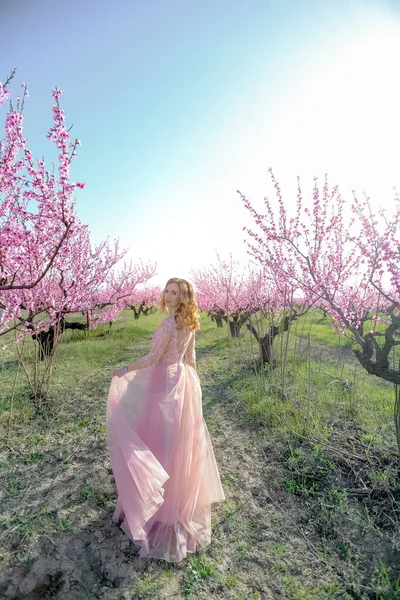 Kvinna i naturlig natur på bakgrunden av blommande persika träd — Stockfoto