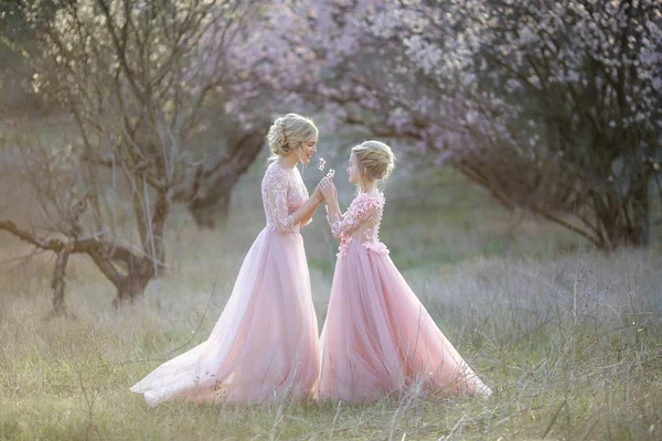 Mãe e filha no jardim em vestidos de moda rosa velho — Fotografia de Stock