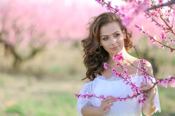Жінка в природі в красивій білій сукні в саду з деревами — стокове фото