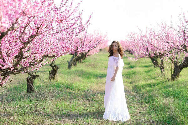 Une belle femme dans une longue robe blanche comme une mariée dans un parc public — Photo