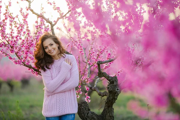 Жінка з природною красою крупним планом дивиться на камеру на тлі весняного молодого квіткового саду — стокове фото