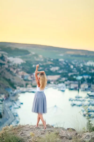 Nő teljes hosszúságú hátsó nézet áll egy hegy felett a tenger öböl csónakokkal — Stock Fotó