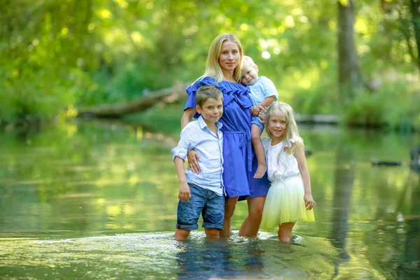 Jeune mère heureuse avec de nombreux enfants en promenade dans les bois avec des enfants près du lac — Photo