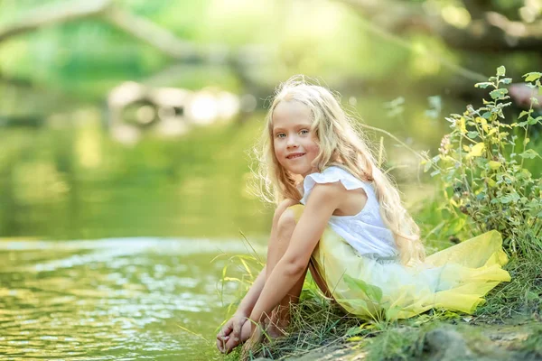 Ragazza 6 anni in un abito giallo brillante vicino al fiume foresta — Foto Stock