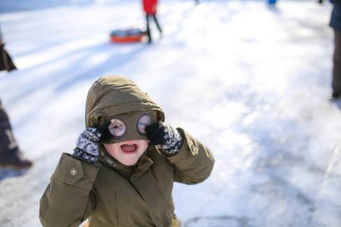 Kışın karlı dağlarda sokakta kızak kayan bir çocuk.