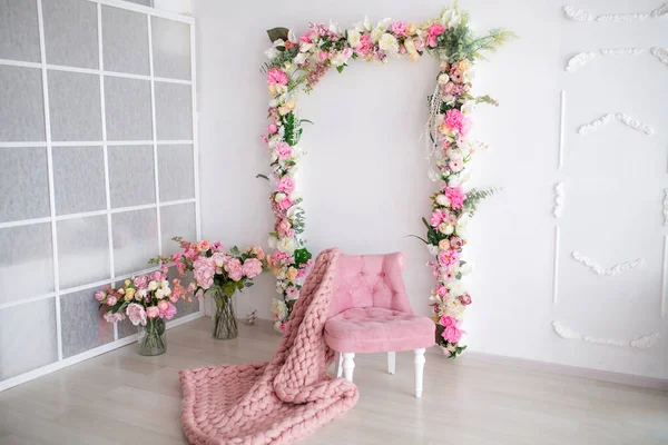 Scenery in the white room. Arch of flowers and a pink armchair with a bouquet of flowers — Stock Photo, Image