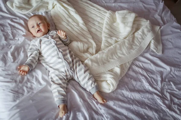 Beautiful little baby boy lying on a white sheet on the bed — Stock Photo, Image