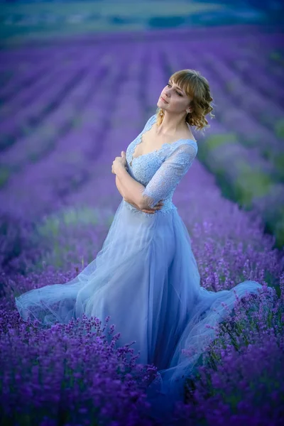 A woman in a brides dress on her wedding day walks through a field of lavender flowers — 스톡 사진
