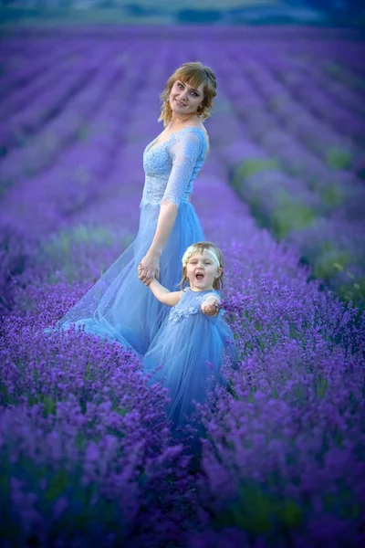 Mother dressed in a wedding dress with her daughter are on the agricultural lavender field — 스톡 사진