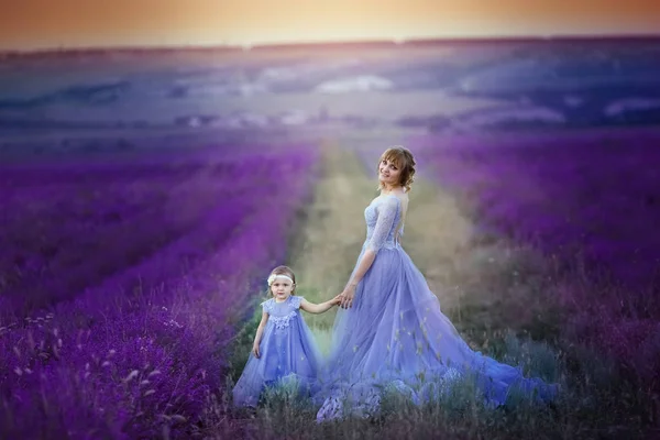 Mother dressed in a wedding dress with her daughter are on the agricultural lavender field — Stock Photo, Image