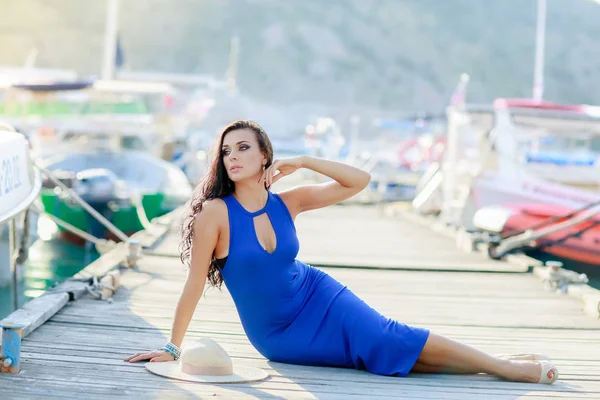 Mavi elbiseli bir kadın tekneler için rıhtımda yatıyor. — Stok fotoğraf