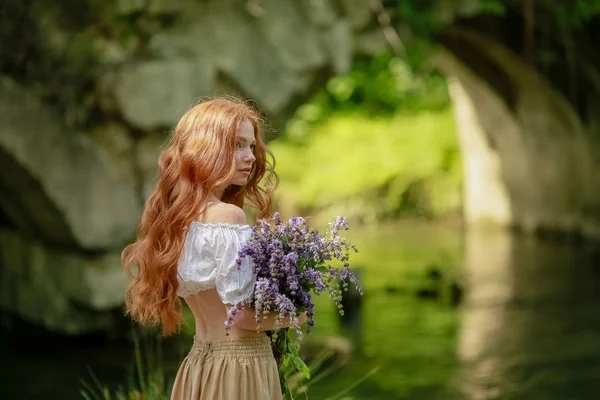 Una donna in abito lungo cammina vicino al vecchio ponte della foresta sul fiume — Foto Stock