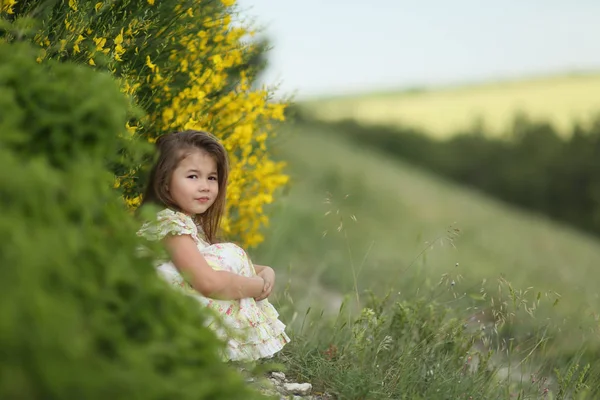 Criança sentada na natureza em um prado com grama verde — Fotografia de Stock