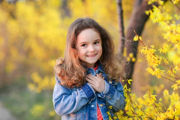 Dítě dívka v džínové bundě na procházce ve žlutém podzimním parku — Stock fotografie