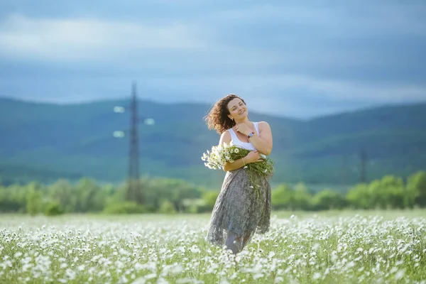 Jovencita alegre con un ramo de flores en las manos de al aire libre — Foto de Stock